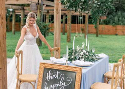 Bride styling a sweetheart table with blue linens and a chalkboard sign