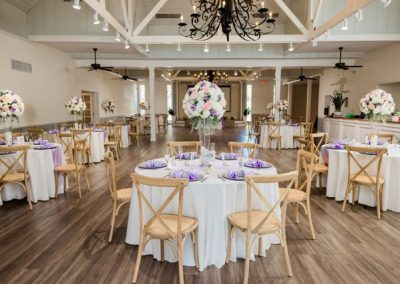 Reception hall set with round tables, lavender napkins and tall floral centerpieces