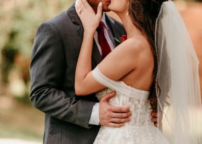 Bride and groom kissing outdoors surrounded by lush green trees