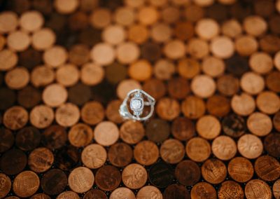 Diamond engagement ring and wedding band resting on a penny-tiled tabletop