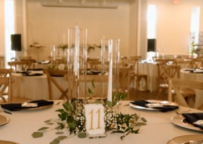 Reception table with gold chargers, black napkins and a greenery centerpiece