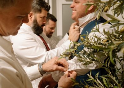 Groomsmen helping the groom fasten his collar before the wedding