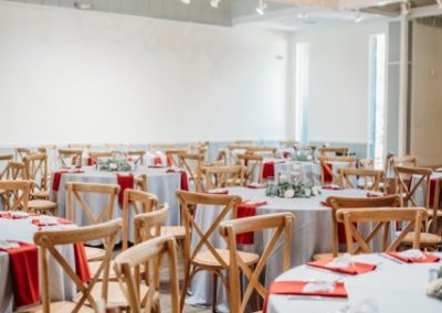 Reception hall with round tables in red and white linens under a wrought-iron chandelier