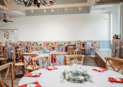 Reception hall with round tables, red napkins and greenery centerpieces