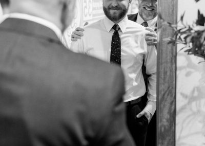 Groom greeting friends before the ceremony, in black and white