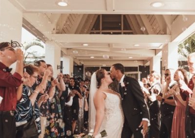 Bride and groom kissing amid a bubble send-off under the covered walkway