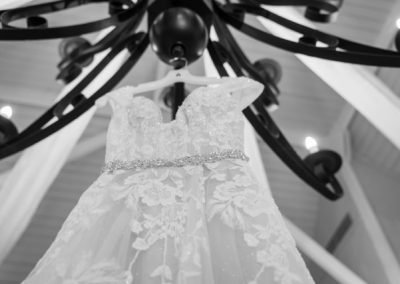 Beaded lace wedding gown hanging from a black wrought-iron chandelier