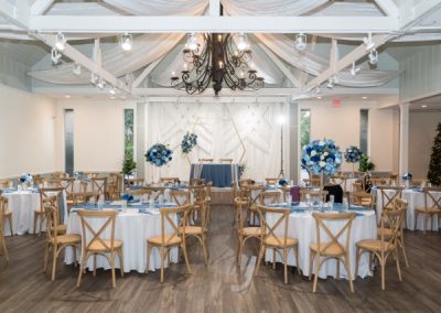 Reception hall set with round tables, blue florals and a hexagon arch backdrop