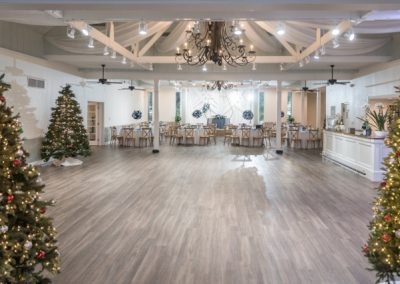 Open reception hall decorated with lit Christmas trees for a holiday celebration