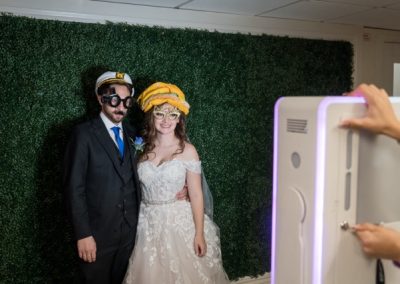 Bride and groom posing at a photo booth in novelty costume glasses and hats