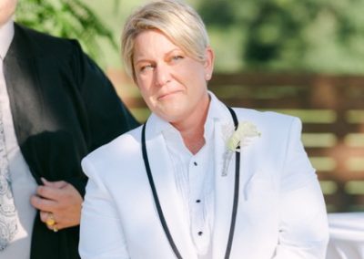 Guest in a white tuxedo and bolo tie watching an outdoor ceremony