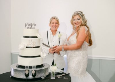 Two brides cutting a tiered black-and-white wedding cake at their reception