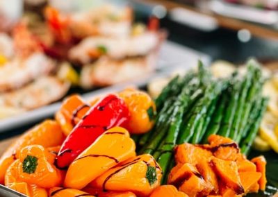 Grilled mini peppers, asparagus and shrimp with balsamic drizzle on a wooden serving board