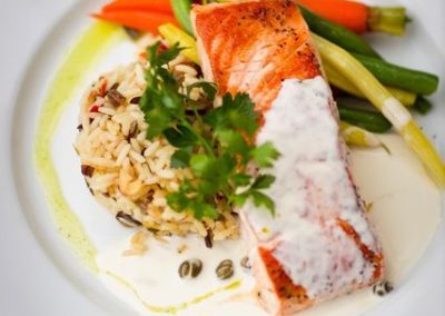Plated salmon with cream sauce, wild rice and seasonal vegetables