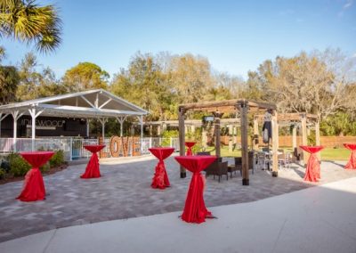 Daytime patio with LOVE marquee letters and red cocktail tables by the pavilion