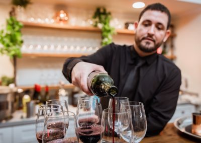 Bartender pouring red wine into stemless glasses at the venue bar