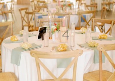 Reception tables with sage napkins, numbered signs and popcorn favors