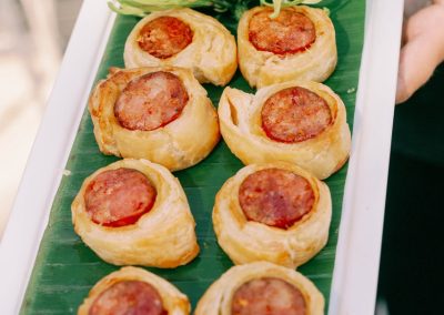 Sausage-stuffed pastry appetizers served on a banana leaf platter