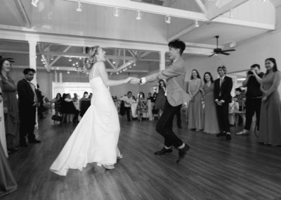 Bride and groom sharing a lively first dance as guests look on