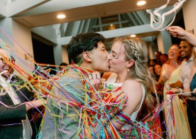 Newlyweds kiss amid a shower of colorful streamers during their send-off