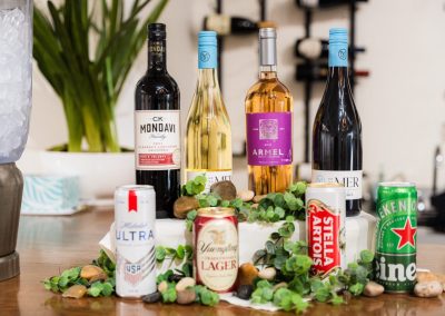 Wine bottles and beer cans arranged with greenery on the venue bar