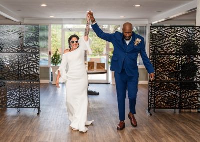 Groom twirls his bride as they enter the reception in a white gown and navy suit