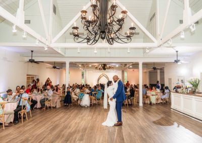 Bride and groom's first dance beneath the ballroom chandelier as guests look on