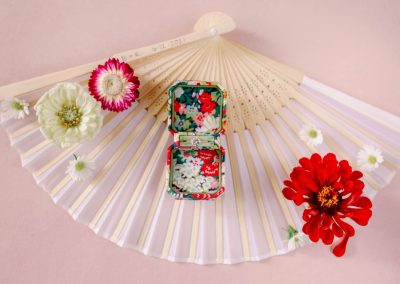 Engagement ring displayed on a folding fan with zinnias and daisies