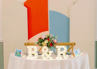 Sweetheart table with lit B and R marquee letters and a colorful modern backdrop