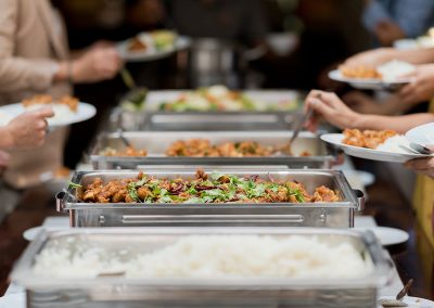 Guests serving themselves from a catered buffet line of stainless chafing dishes