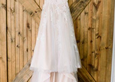 Blush lace wedding gown hanging on a rustic wooden barn door