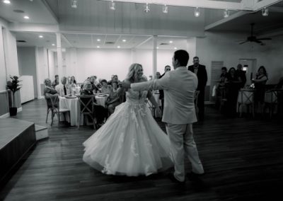 Black-and-white first dance in the reception hall as seated guests look on