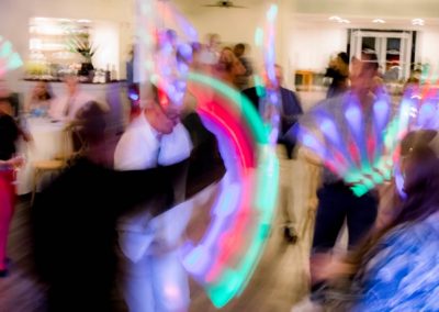 Guests dancing with colorful glow lights in a motion-blurred reception shot