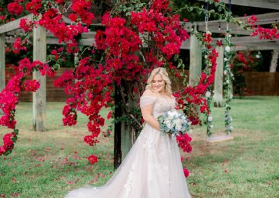 Bride holding a bouquet beneath cascading magenta bougainvillea
