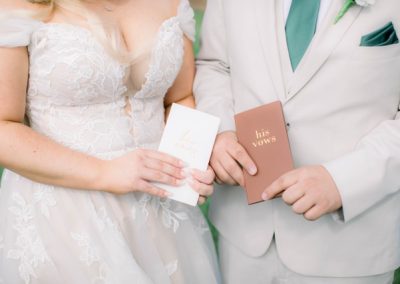 Bride and groom holding his-and-hers vow booklets, hands in close-up