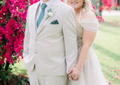 Bride and groom holding hands beside vivid pink bougainvillea