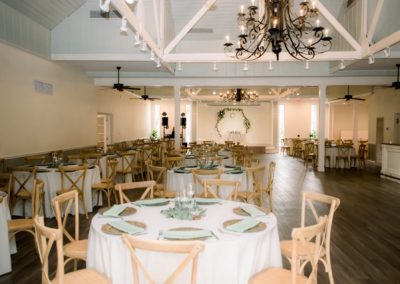 Reception hall with round tables, sage green napkins and iron chandeliers
