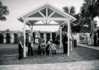 Black-and-white view of guests mingling under a white garden pavilion