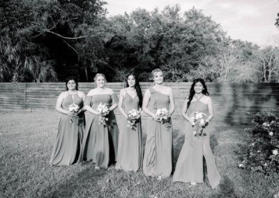 Bridesmaids in green gowns holding bouquets on the lawn