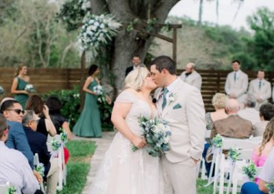 Bride and groom kissing at the end of the aisle after their outdoor ceremony