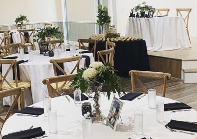Round reception table set with white linens, black napkins and a greenery centerpiece