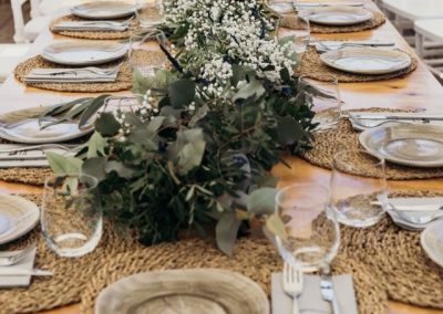 Long farm table set with woven placemats and a eucalyptus and baby's breath garland
