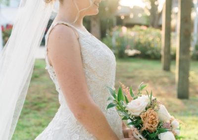 Bride holding her bouquet in golden sunset light on the venue grounds
