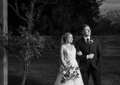 Bride and groom beneath the Idlewood Biergarten sign, in black and white