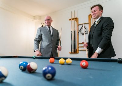 Two groomsmen playing a game of pool in the venue billiards room